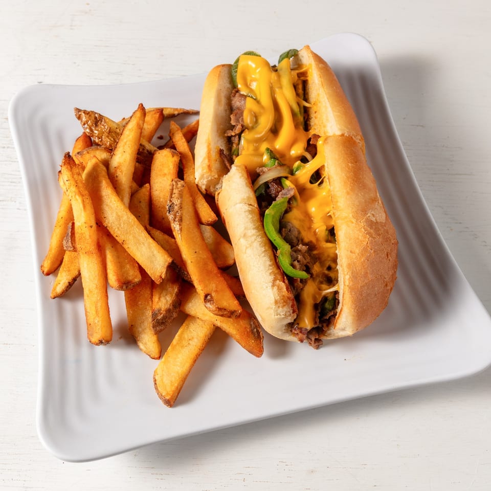 A Pierce Street Bagel Cafe Deli & Grill cheesesteak with fries on a white plate.