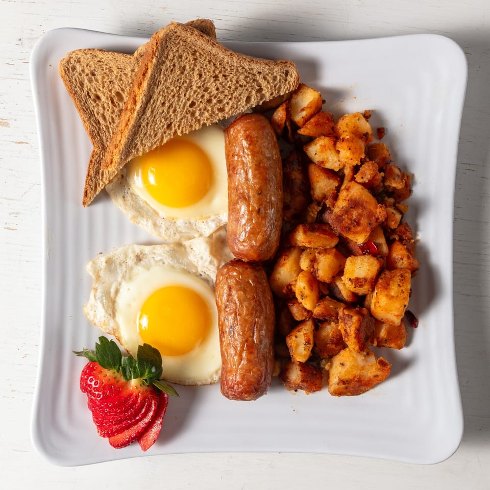 Pierce Street Bagel Cafe Deli & Grill breakfast platter with eggs, sausage, home fries, toast, and strawberries.